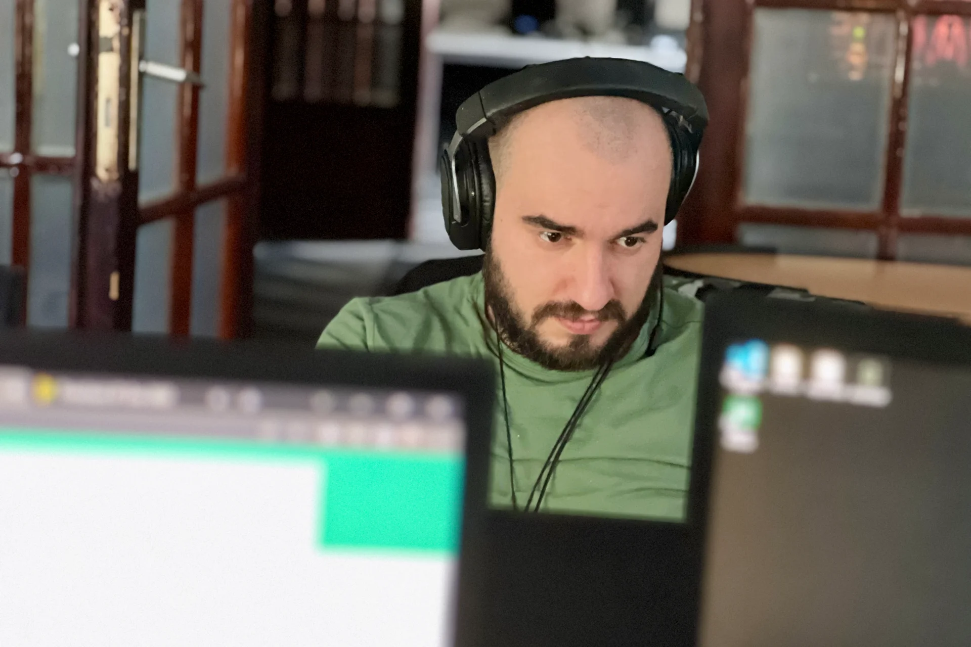 Un dezvoltator web concentrat la cod, cu căști pe urechi, lucrează de la computerul său din biroul Codezilla.