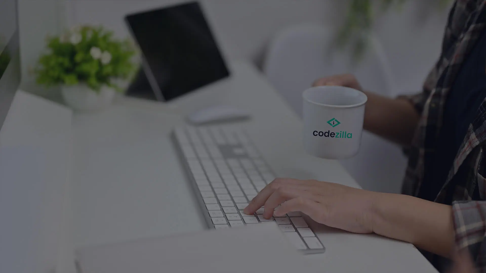 Codezilla employee working and drinking from a branded mug.