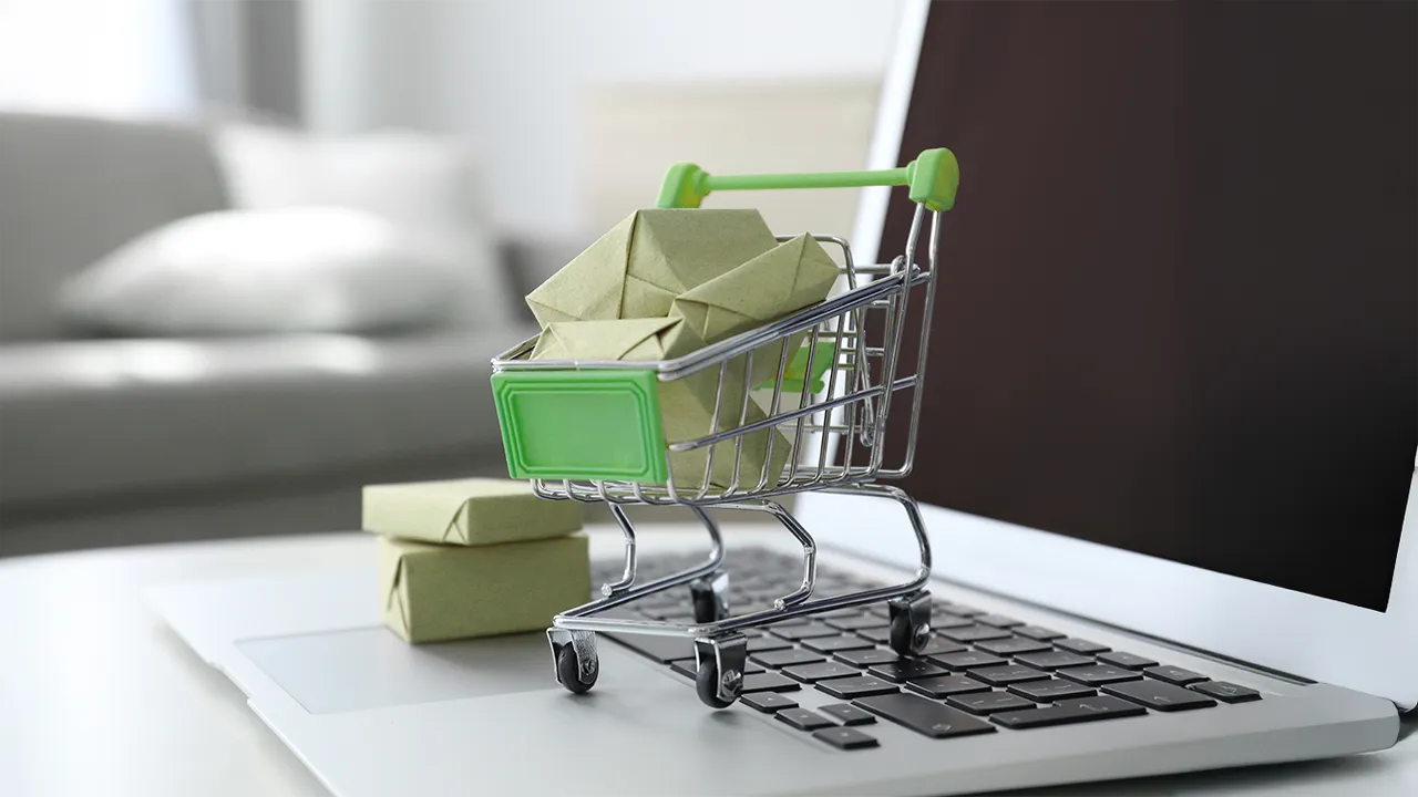 Miniature shopping cart with packages placed on a laptop keyboard, symbolizing online commerce