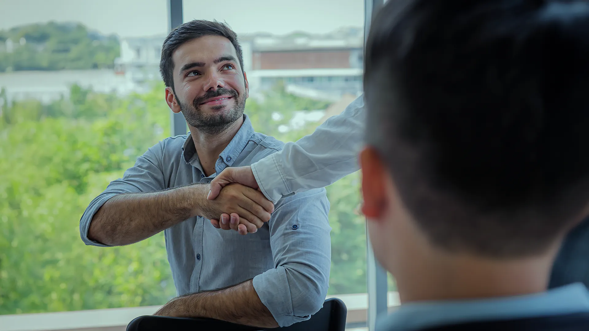 Programator strângând mâna unui nou coleg, într-un birou modern, într-un moment care sugerează integrare și începutul unui nou parcurs profesional