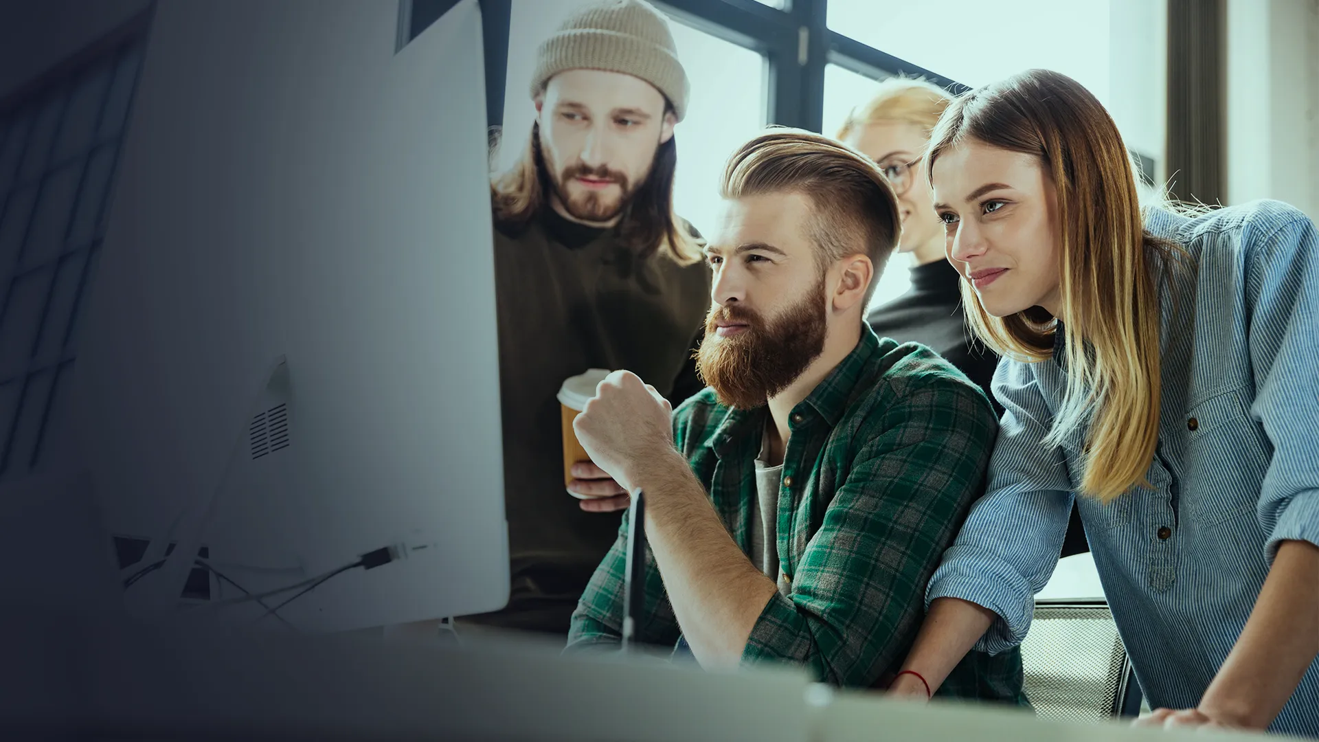 Team collaborating around a monitor in a modern office while developing digital solutions