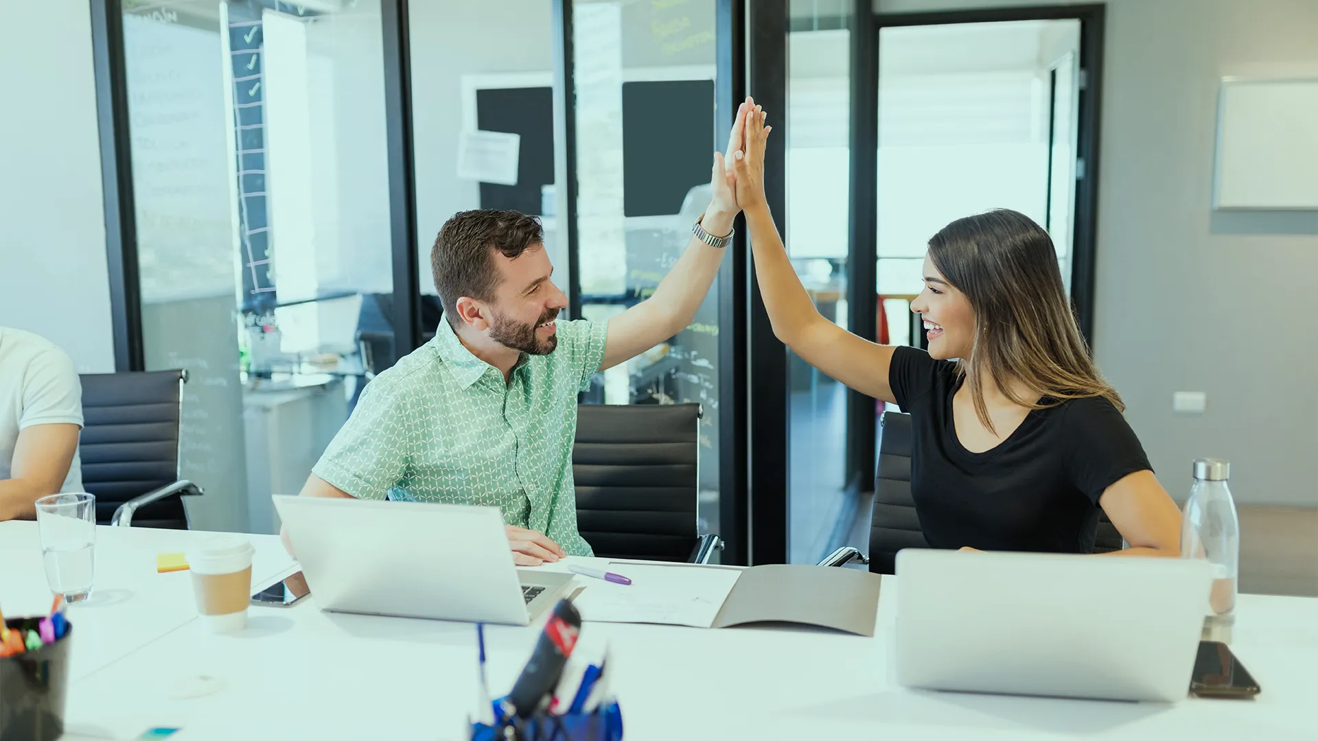 Web developers celebrating an achievement with a high-five in a modern, collaborative office