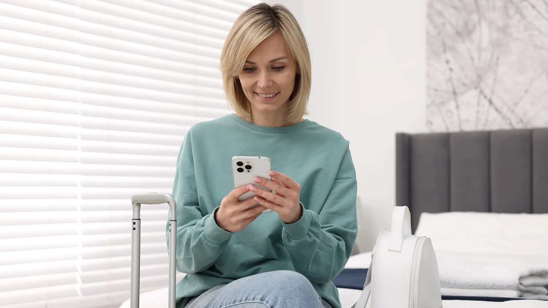 Woman checking travel information on her mobile phone next to her holiday luggage