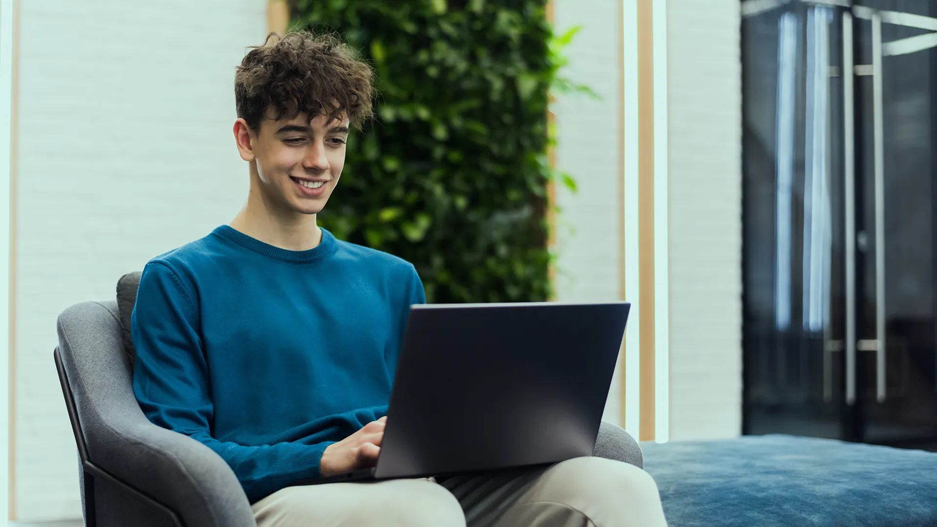 Young person working on a laptop in a modern office space, suggesting learning and professional growth